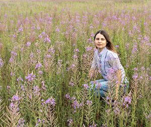 Portrait of woman with purple flowers on field