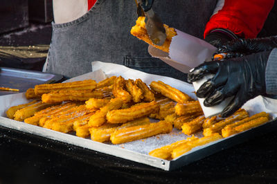 Midsection of person making churros at market stall