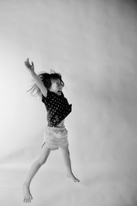 Full length of girl jumping by wall