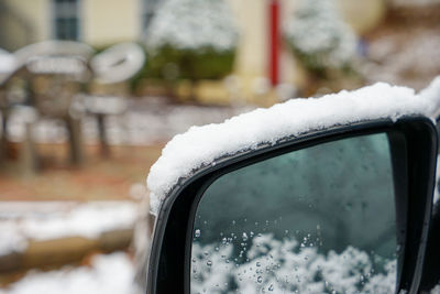 Close-up of snow covered car on side-view mirror