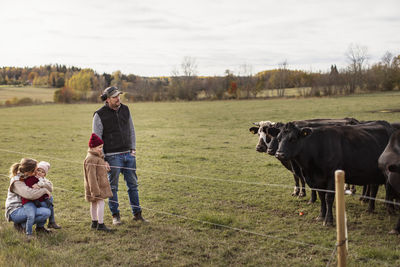 Girls with parents watching cows in farm