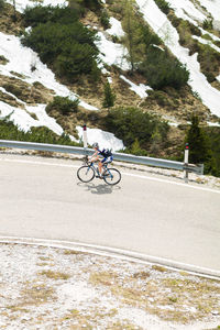 Woman riding bicycle on road by snowy mountain