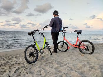 Rear view of man with bicycle on beach