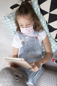 Girl using mobile phone on sofa at home