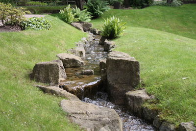 Stream amidst grassy field in park