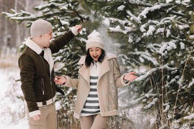 A man and a woman in love walk in a snowy forest among trees in the winter countryside in nature