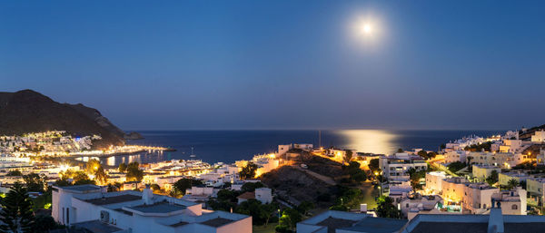 High angle view of illuminated buildings by sea against sky