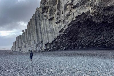 Person walking by rock against sky