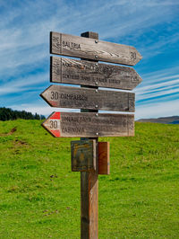 Information sign on wooden post on field against sky