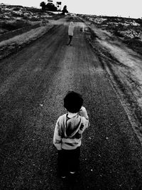Rear view of boy standing on road