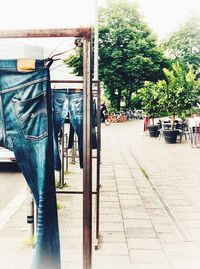 Clothes hanging on footpath in city against blue sky