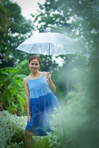Portrait of a smiling woman standing in rain