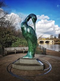 Statue of bare tree in city against sky