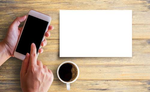 Directly above shot of hand holding coffee cup on table
