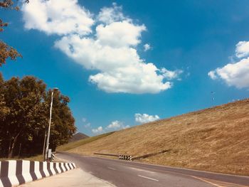 Empty road along landscape and trees against sky