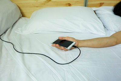 High angle view of man using mobile phone on bed