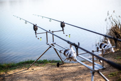 Fishing rod on railing by lake against sky