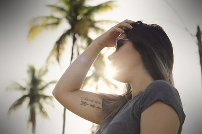 Portrait of woman photographing against sky