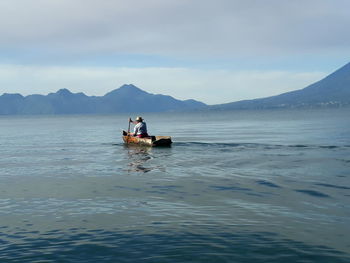 People in boat on lake against sky