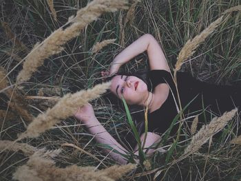 High angle portrait of teenage girl lying down on land by plants