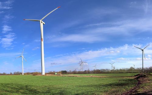 Windmills on field against sky