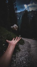  cropped hand of man throwing rock outdoors at night