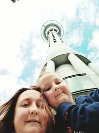 Low angle portrait of mother and daughter against sky tower