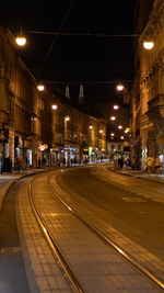 Illuminated street by buildings in zagreb at night