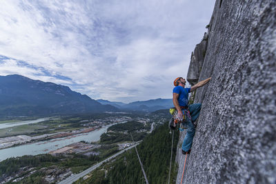 Man looking up while rock climbing squamish chief on granite with view