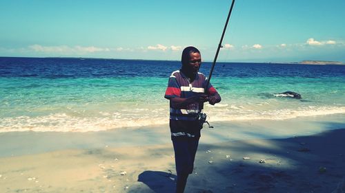 Man with fishing rod walking at beach