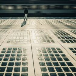 Rear view of man standing on railroad station platform against moving train