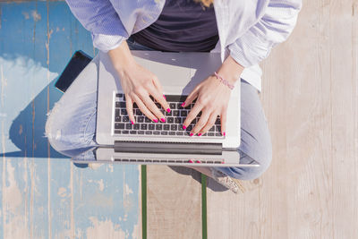 Young woman with laptop sitting on jetty