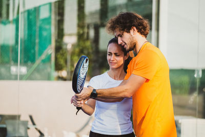 Young man holding woman standing against wall