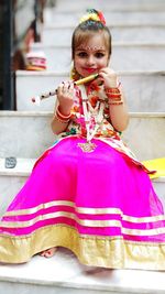 Portrait of smiling cute girl wearing traditional clothing while sitting on staircase