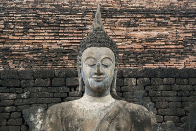 Statue of buddha against brick wall