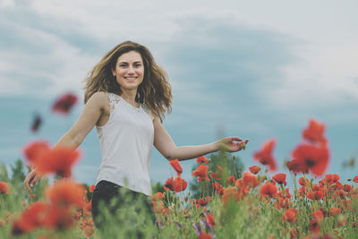 Smiling young woman with red flowers against blurred background