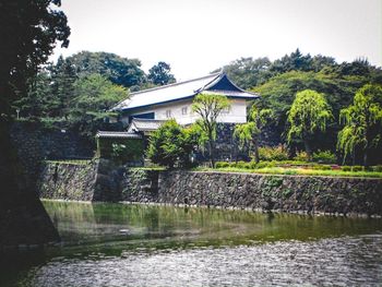 House by lake and building against sky