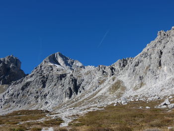 Low angle view of snowcapped mountains against clear blue sky