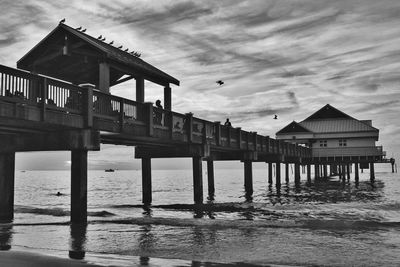 Pier on sea against cloudy sky