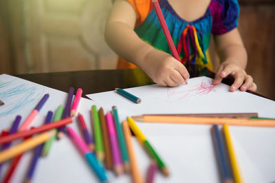 Midsection of man holding pencils on table