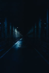 Empty road in illuminated tunnel at night