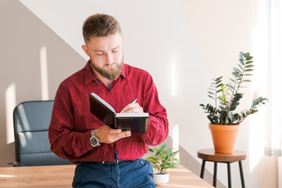 Budget planning. pensive bearded man writing in a notebook while sitting