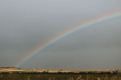 Scenic view of rainbow against sky during rainy season
