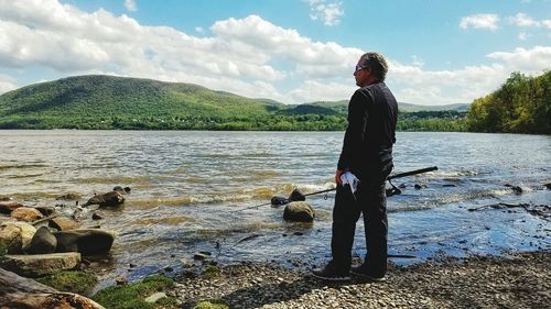 Man standing on riverbank against sky