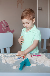 Cute boy playing on table at home