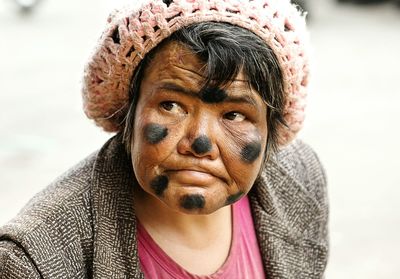 Mature woman with black face paint on face looking away outdoors