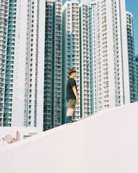 Woman standing by modern buildings in city