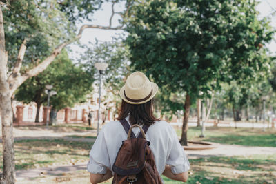 Rear view of woman standing against trees