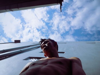 Directly below shot of shirtless man standing against building