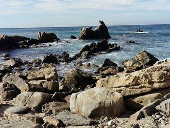 Rocks on sea shore against sky